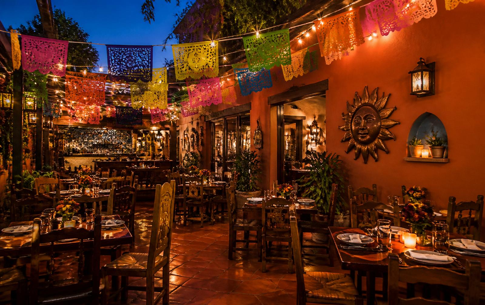 Warm El Loro dining room glowing with string lights and papel picado